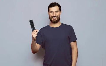 En man håller i en plattborste till skägg. 