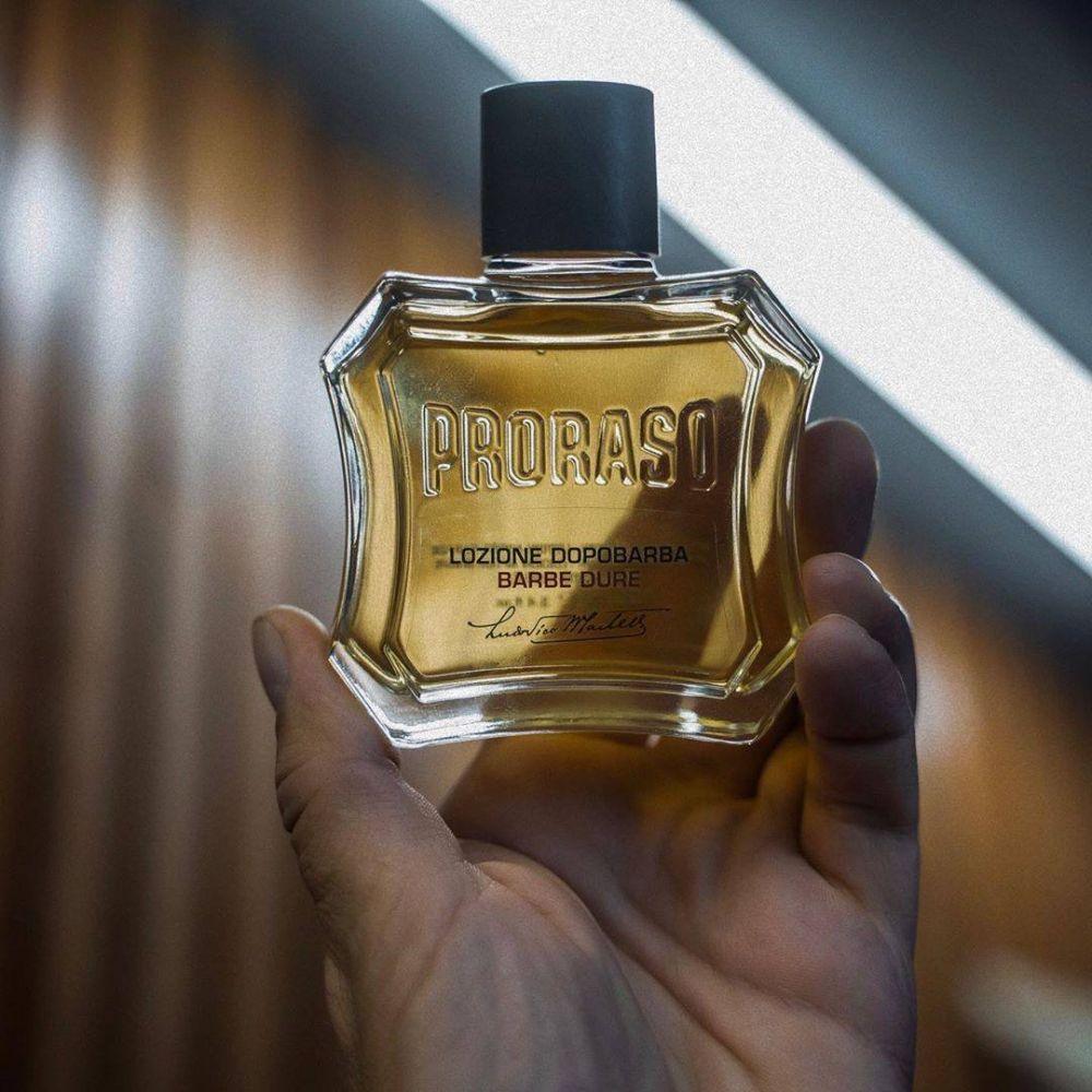 En person som håller i en flaska Proraso After Shave Lotion - Närande.